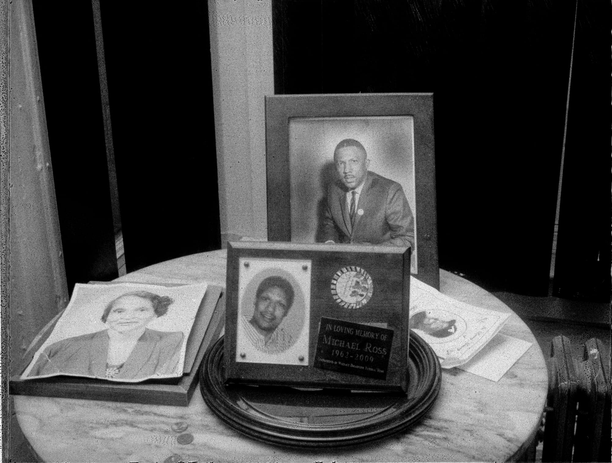 A black-and-white photograph by Carlos Javier Ortiz of framed portraits of Clyde Ross and his family