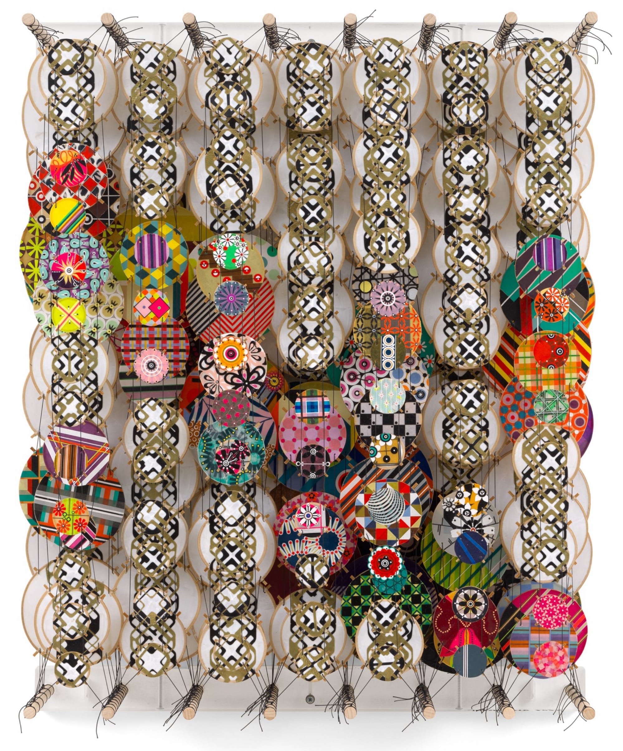 an abstract artwork by Jacob Hashimoto made from twine and numerous colorful, patterned paper discs installed in rows for a layered effect