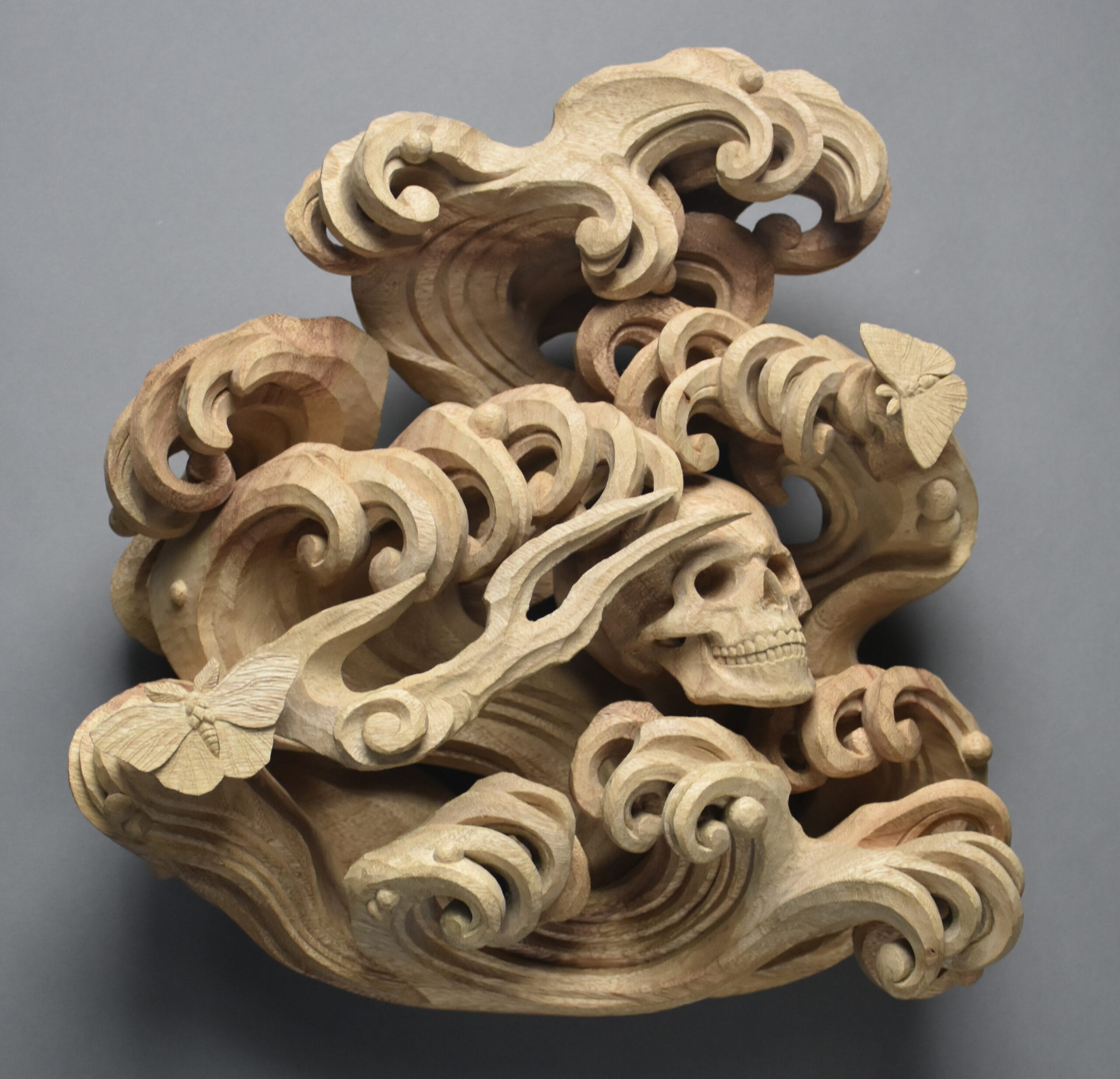 a carved wood sculpture by Kosuke Ikeshima of a skull and wave shapes