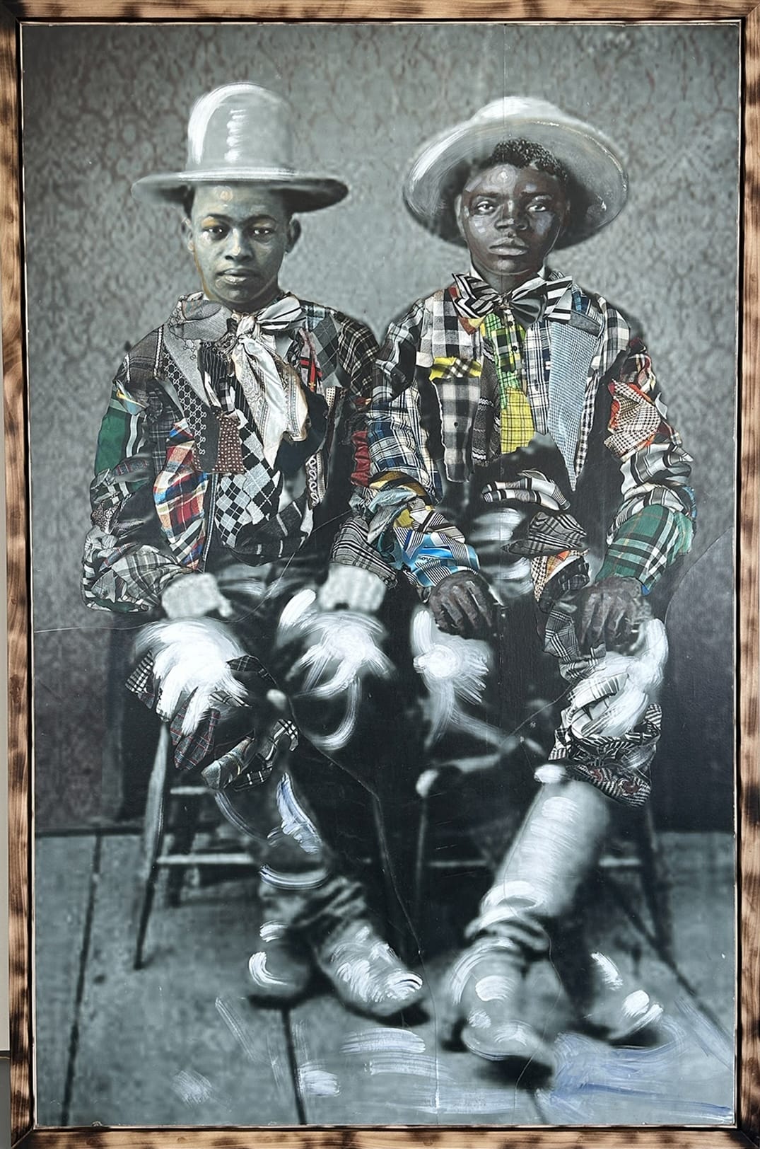 a framed portrait by Stan Squirewell, from an old photograph, of two young, seated Black men with colorful, patterned fabrics collaged onto the image