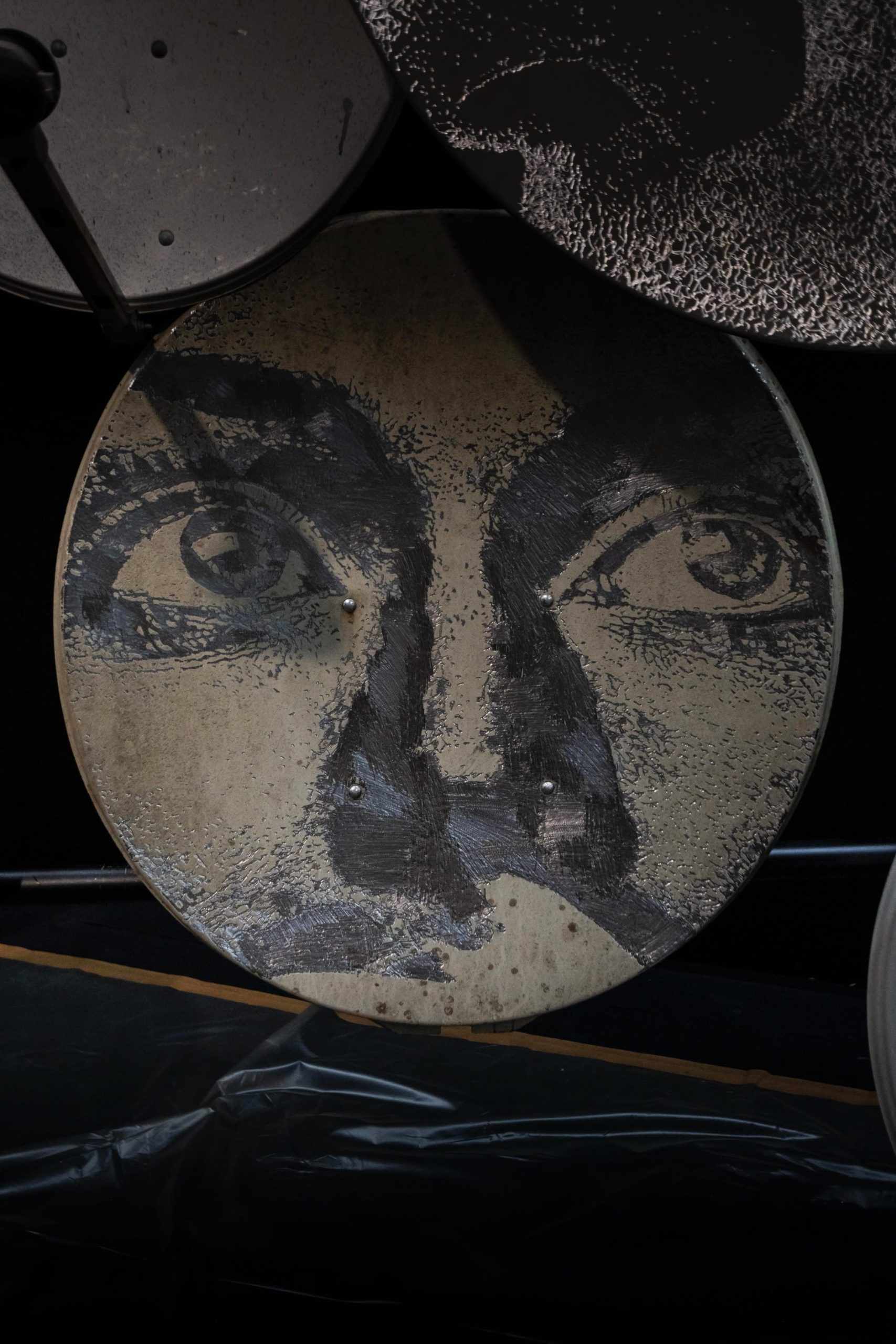 a detail of a face painted on a circular form by Vhils